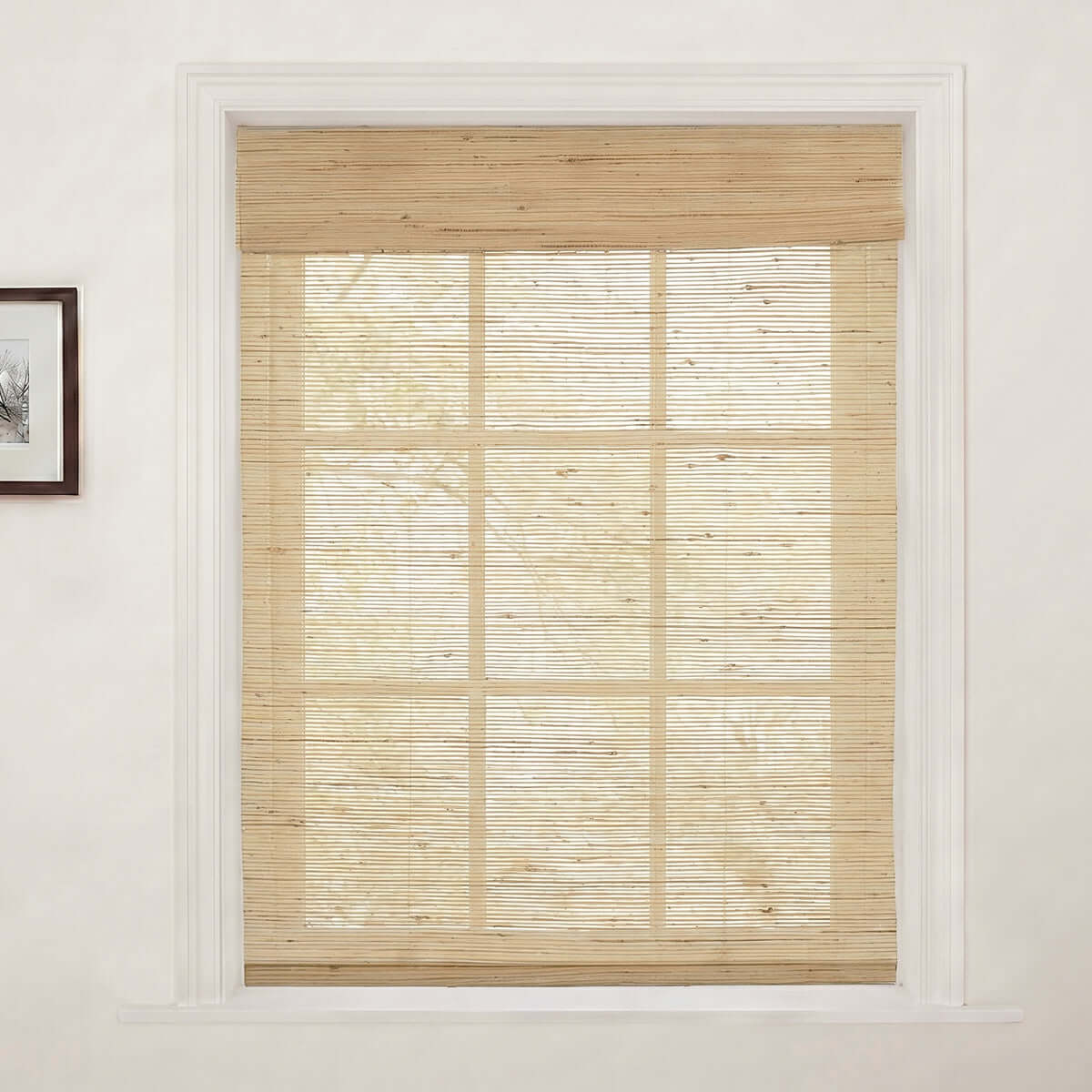Berissa Natural Soft Glow Woven Bamboo Roman Shade in a window, showcasing natural light filtering through.